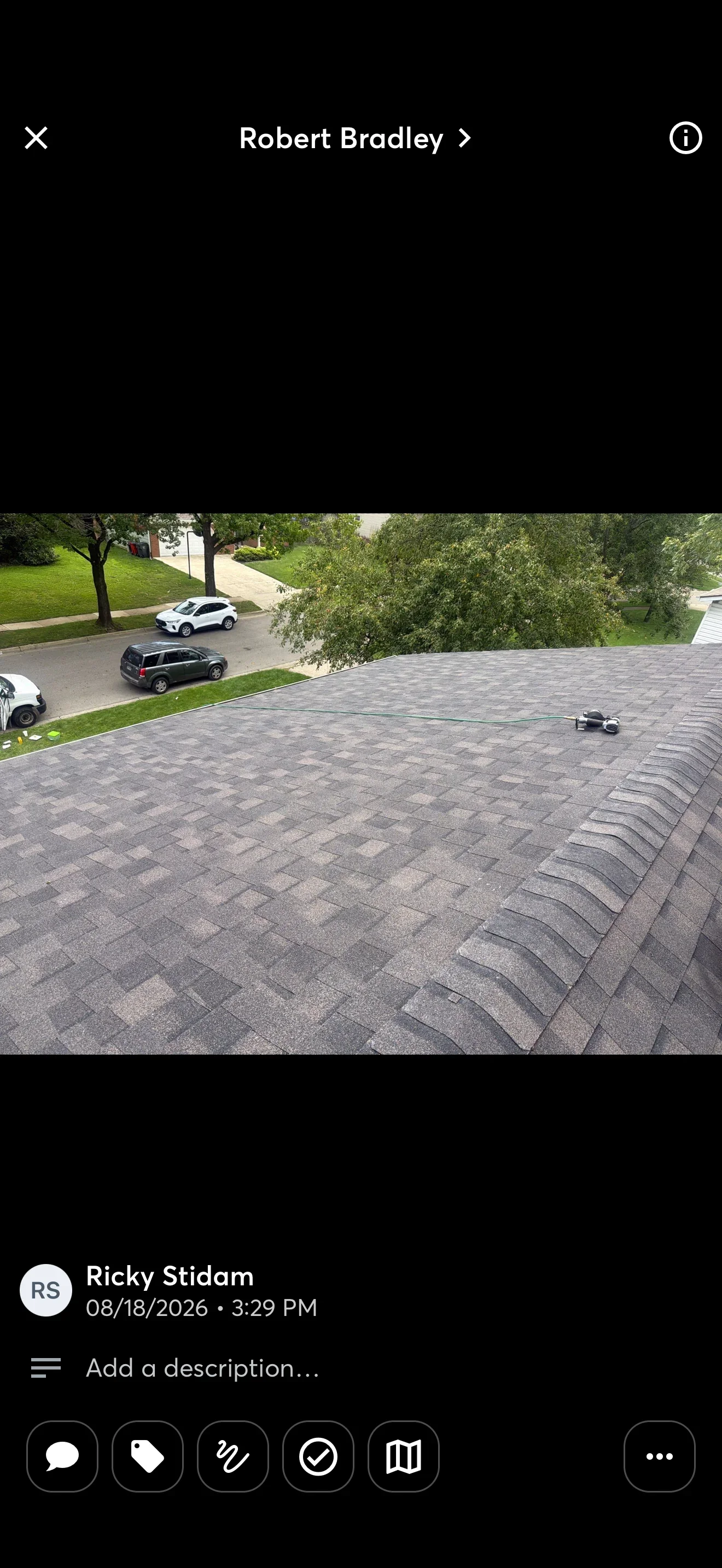 Gray dimensional asphalt shingle roof with ridge caps and pneumatic nailer on the roof surface